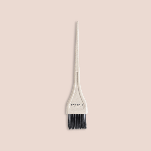 A single hair dye applicator brush with a textured off-white handle and black bristles, centered on a solid pale pink background. The brand name 'NAR HAIR' is printed on the ferrule.