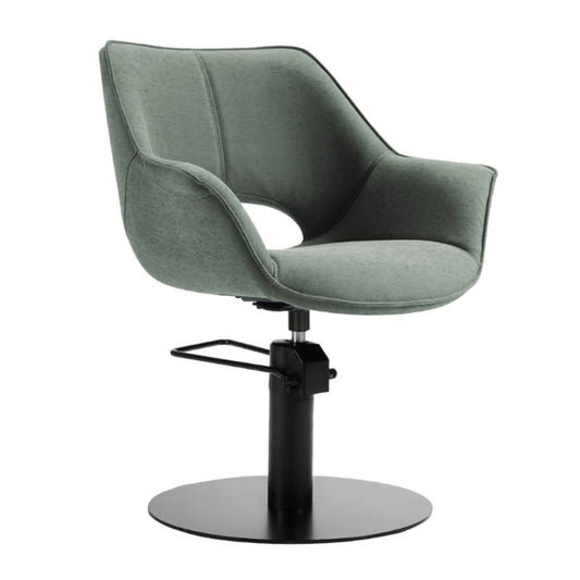 A modern swivel salon chair with a curved upholstered seat and back in a muted sage green fabric, supported by a black metal pedestal base with a circular footplate and a small footrest.