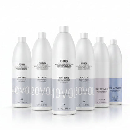 Six white bottles of Nix Hair permanent hair color developer and developer activator, arranged in a row against a white background. The bottles are labeled with different developer strengths (40Vol, 50Vol, 60Vol, 70Vol, 80Vol) and include a purple tone activator bottle on the right.