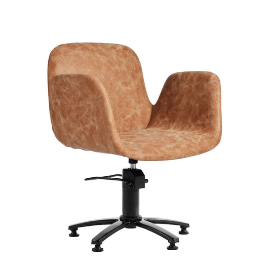 A modern swivel salon chair with a rounded, sculptural seat upholstered in a textured tan faux-leather material, mounted on a black five-star swivel base.